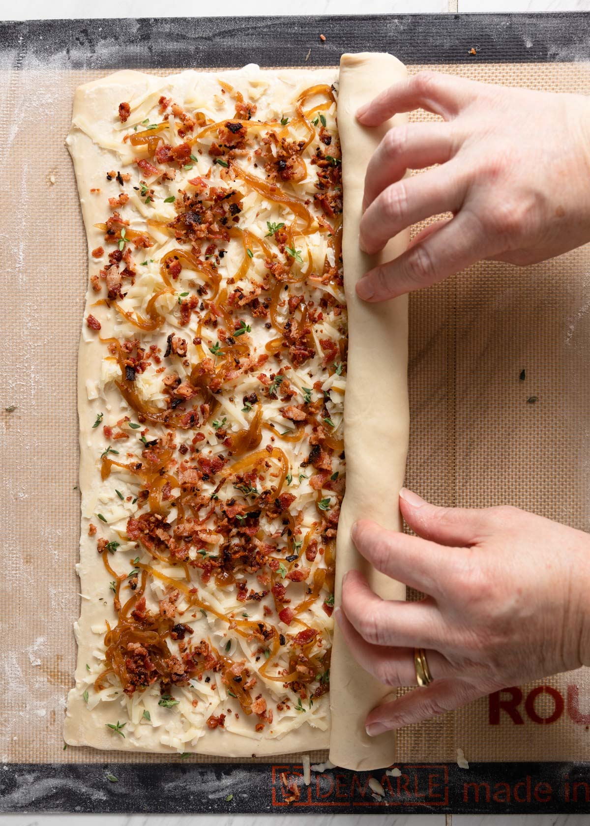 rolling bacon, caramelized onion, and gruyere puff pastry into palmiers