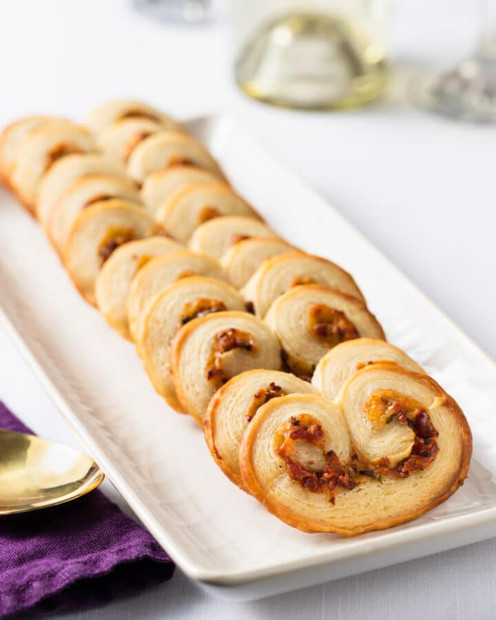 savory palmiers with bacon and gruyere on a white serving plate