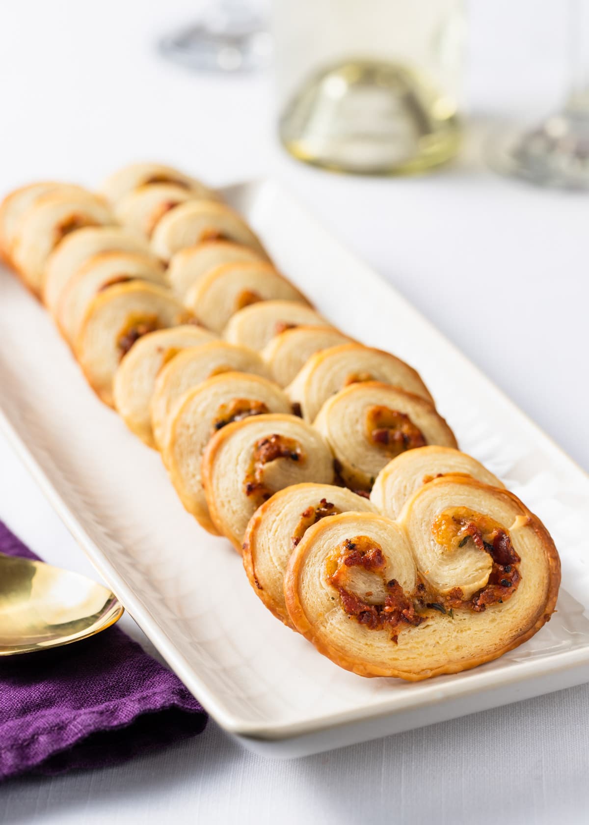 savory palmiers with bacon and gruyere on a white serving plate