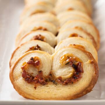 closeup of savory palmiers with bacon on a white serving platter