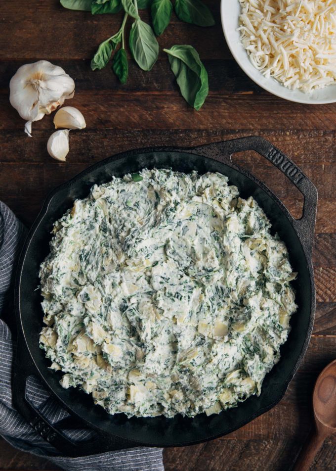 unbaked spinach artichoke dip in a round cast iron pan