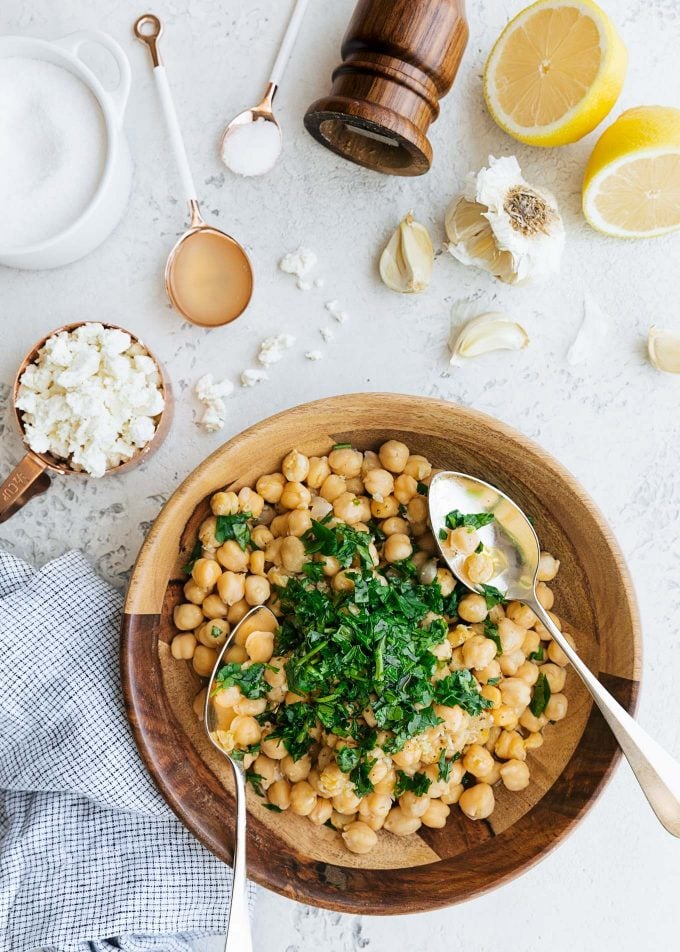 overhead photo of mixing garbanzo bean salad ingredients in a wooden bowl