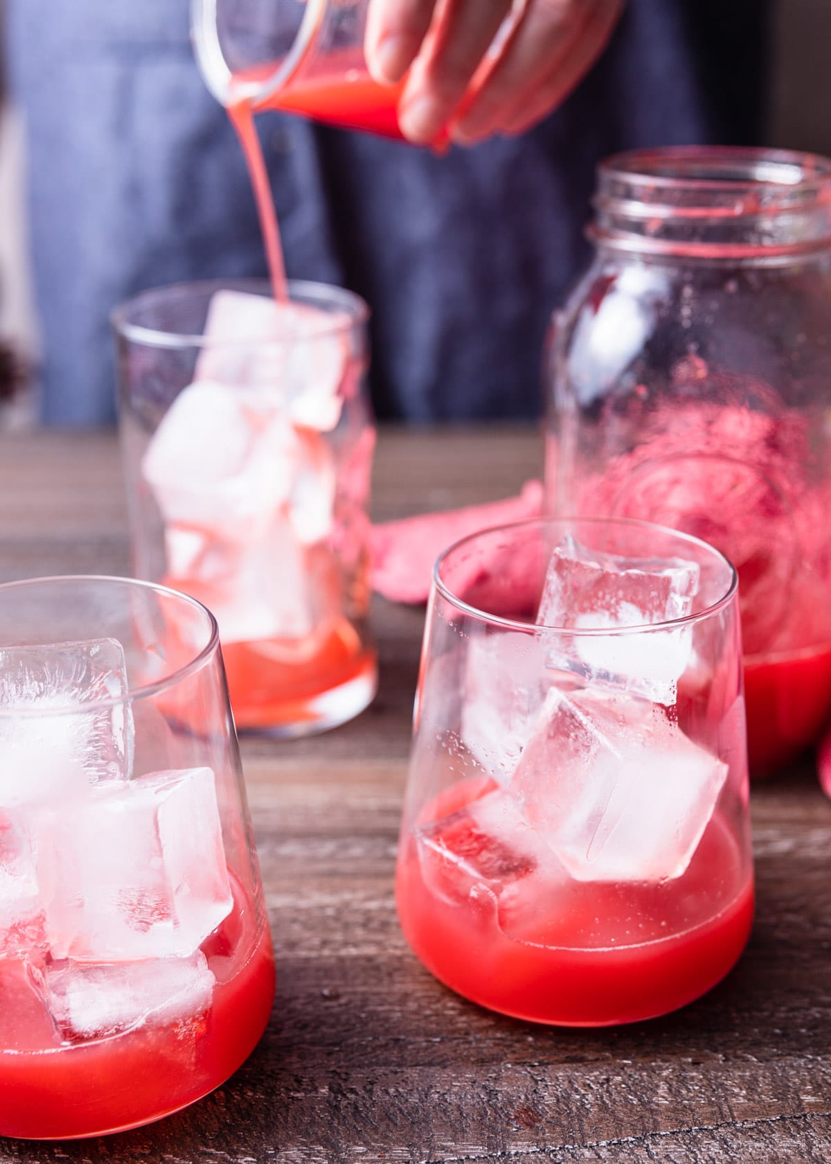 basil and strawberry syrup poured into ice filled glasses