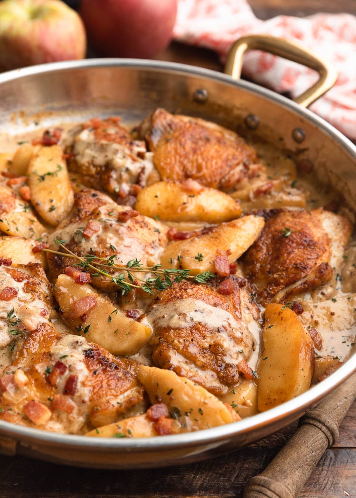 side view of hard cider chicken with bacon and apples in a copper frying pan