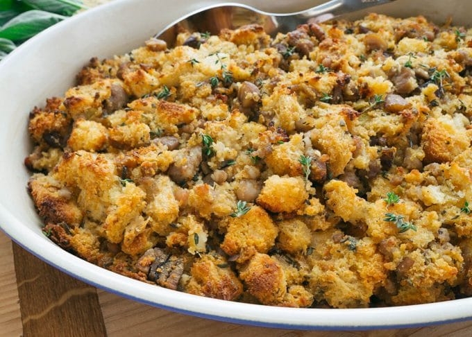 baked cornbread stuffing with sausage and chestnuts in a pan with a serving spoon