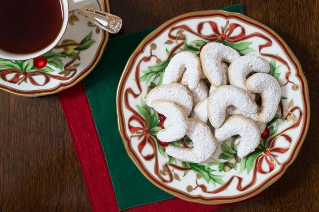 walnut crescent cookies dusted with powdered sugar on a Christmas pattern plate