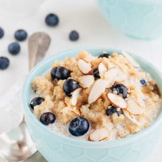 breakfast quinoa with blueberries and sliced almonds in a teal bowl