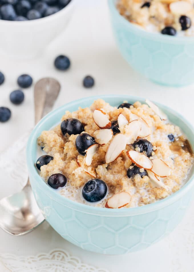 breakfast quinoa with blueberries and sliced almonds in a teal bowl