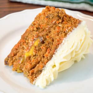 a slice of orange curd filled carrot cake with cream cheese frosting on a white plate