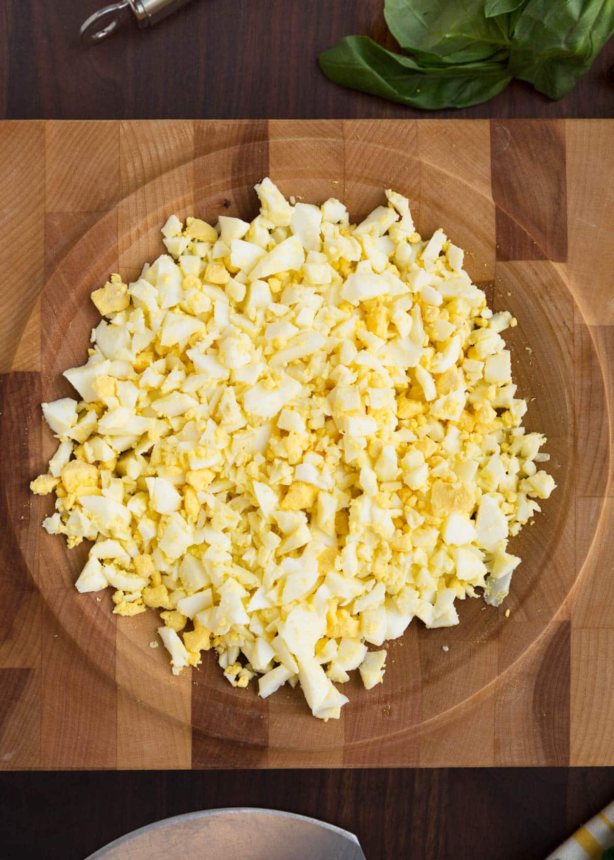 chopped hard boiled eggs in a wooden mincing board (overhead)