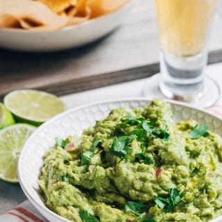 grilled guacamole in a serving bowl with a dish of tortilla chips