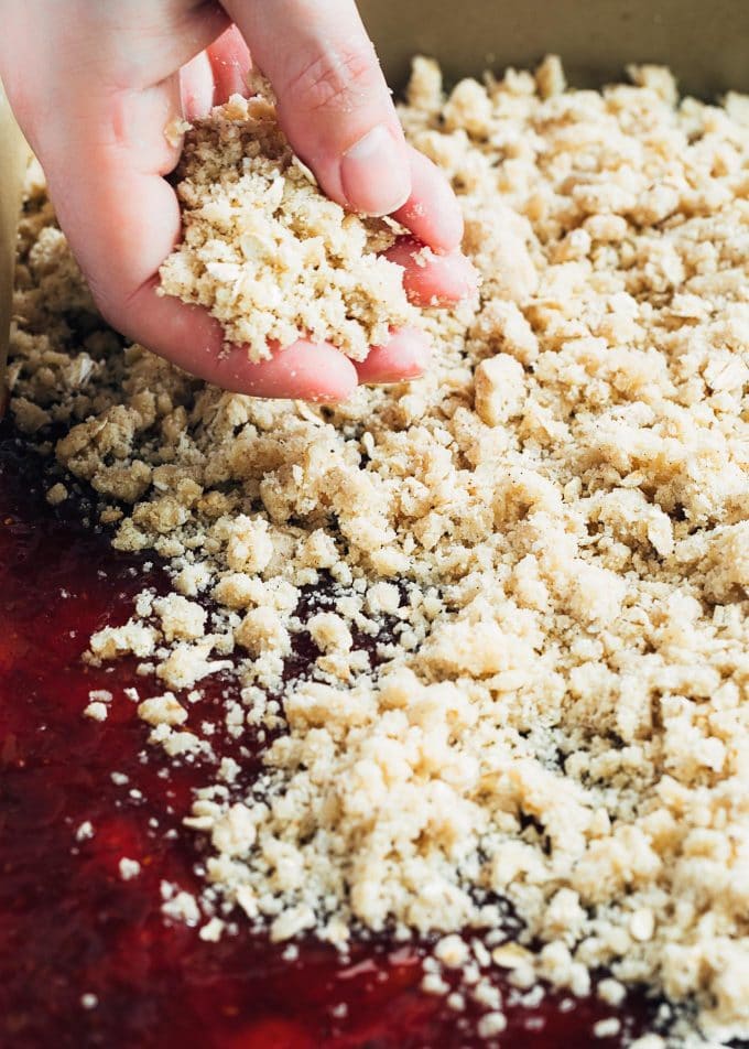 sprinkling crumble topping over jam bars