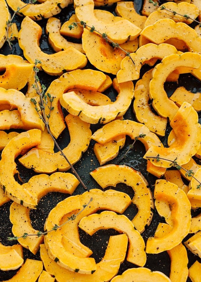 raw delicata squash rings on baking sheet with thyme