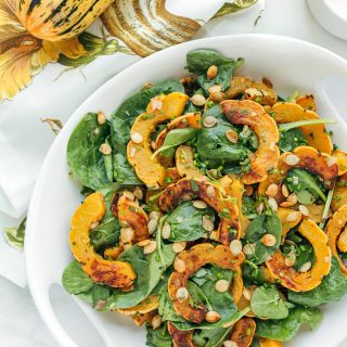 delicata squash salad with baby spinach and brown butter vinaigrette in a white serving bowl