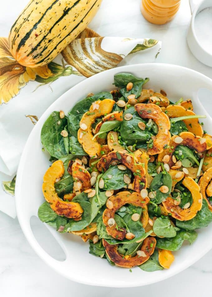 delicata squash salad with baby spinach and brown butter vinaigrette in a white serving bowl