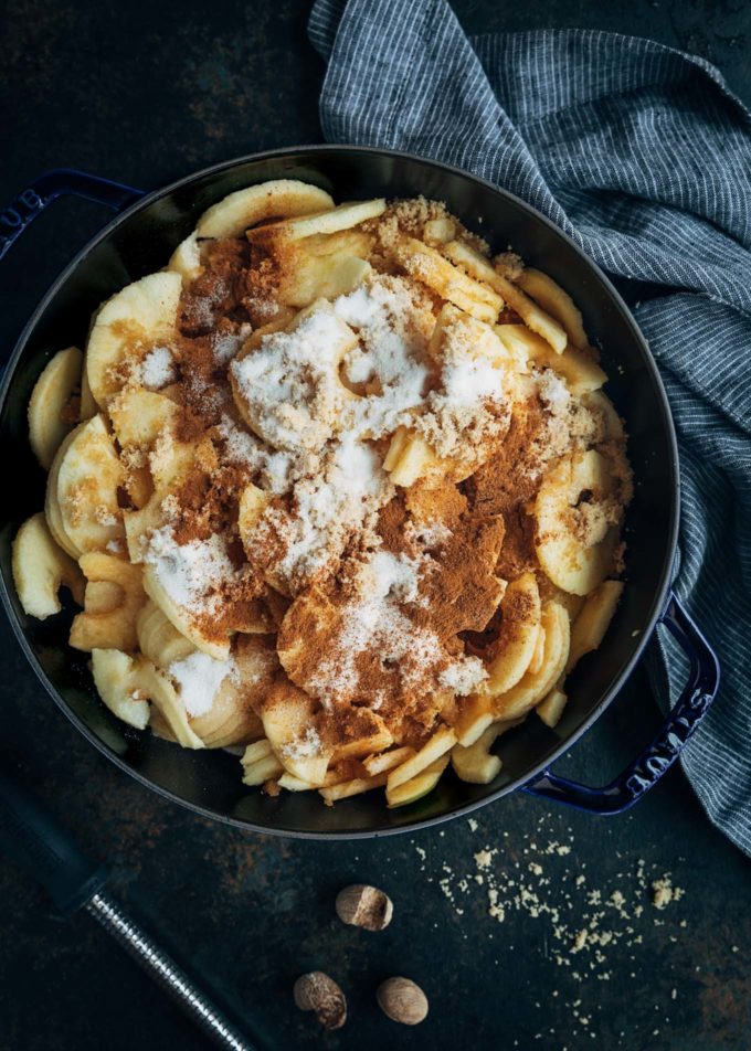 raw apple slices in a pot with cinnamon, brown sugar, and granulated sugar