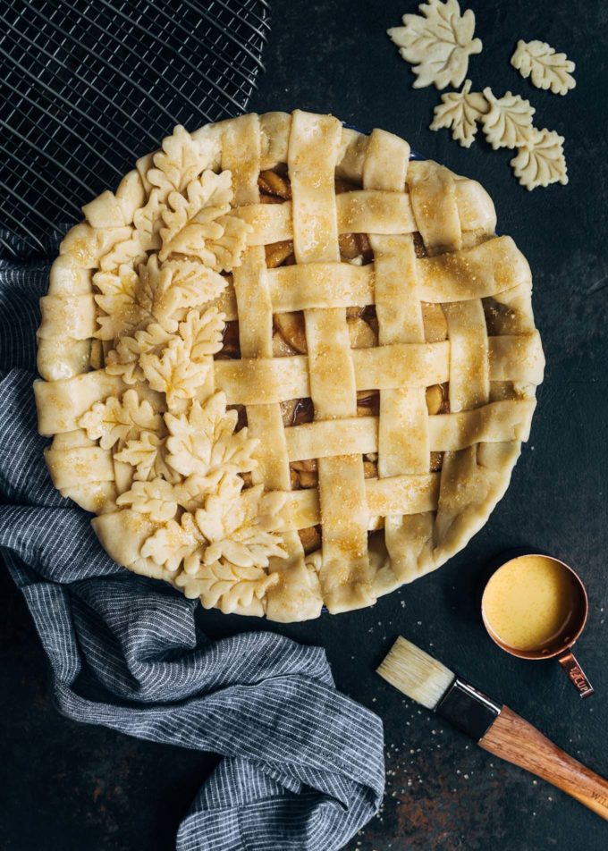 unbaked lattice apple pie on a board with egg wash and a pastry brush