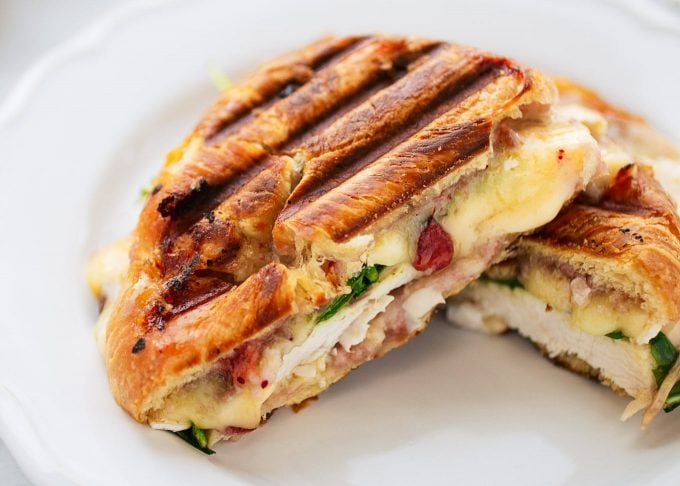 Turkey Croissant Panini with melted brie and cranberry sauce cut in half on a white plate