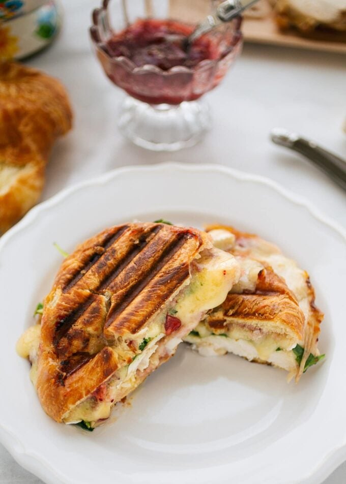 grilled turkey and brie croissant panini cut in half on a white plate