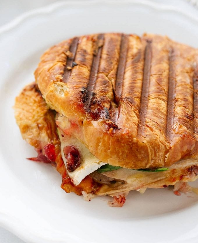 whole grilled turkey croissant panini on a white plate