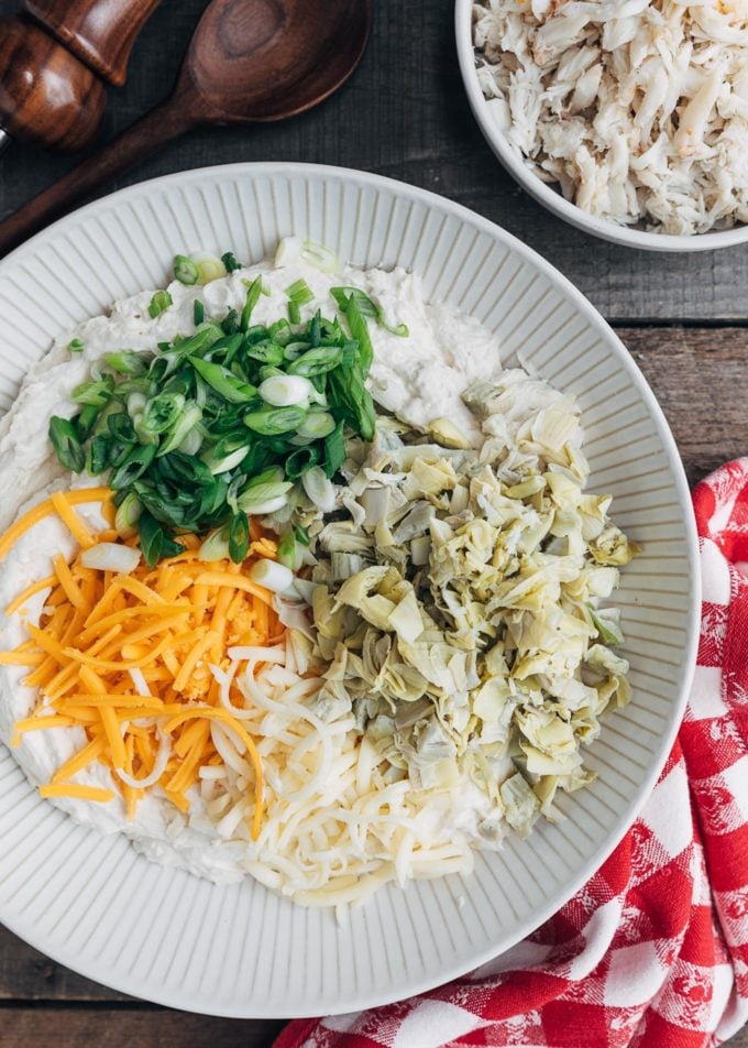 cheddar and jack cheeses, artichoke hearts, and scallions in a bowl for crab dip