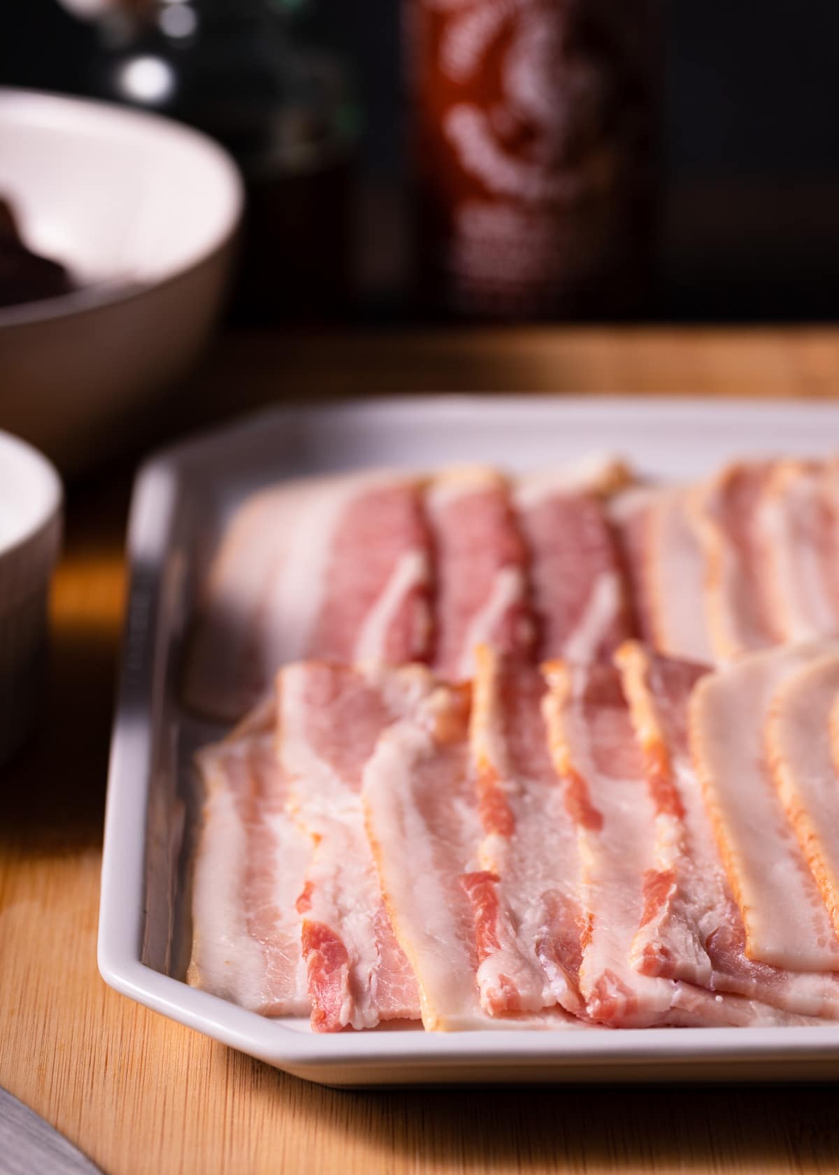 raw bacon strips on a white platter