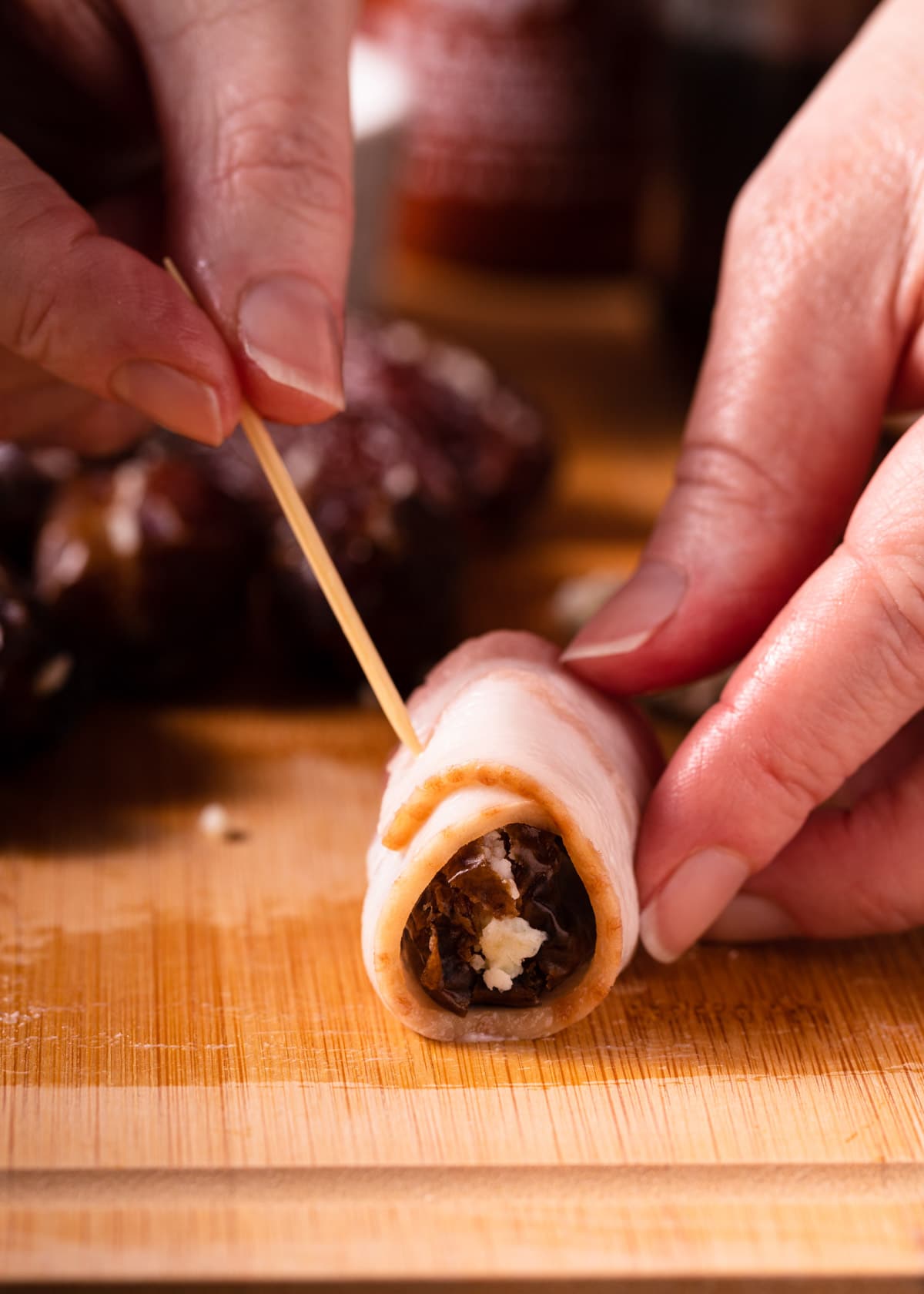 bacon wrapped date being skewered closed with a soaked toothpick