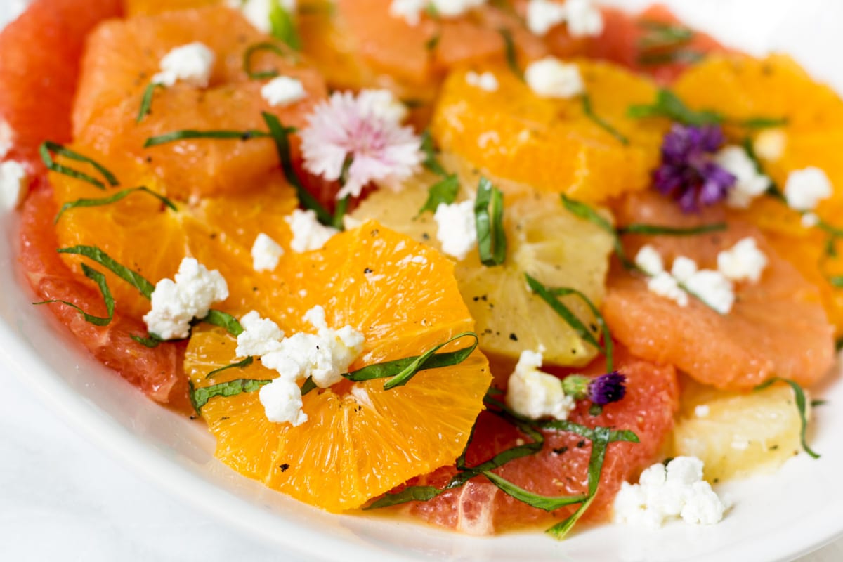closeup of citrus salad with goat cheese on a white platter