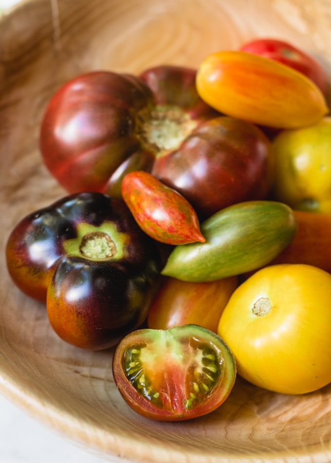 assorted heirloom tomatoes in a hand-carved wooden bowl