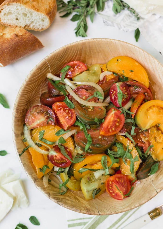 heirloom tomato salad with onions and basil in a wooden bowl