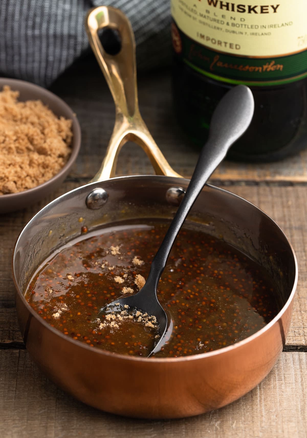 whiskey mustard glaze in a small copper pot with a black spoon