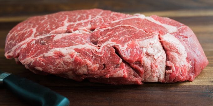 whole marbled beef chuck roast on a cutting board