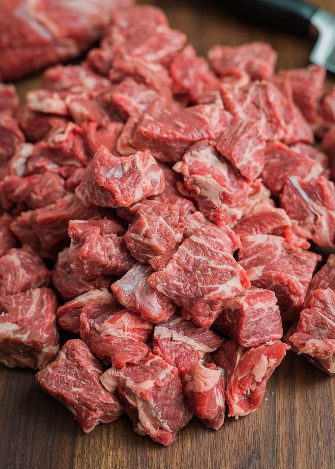 chuck beef cut into cubes for grinding on a cutting board