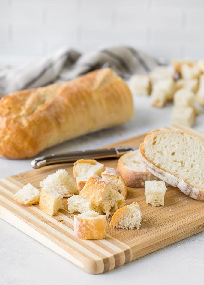 pane francese a cubetti su un tagliere di legno per crostini fatti in casa