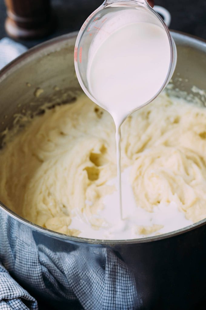 pouring half and half into cream cheese mashed potatoes