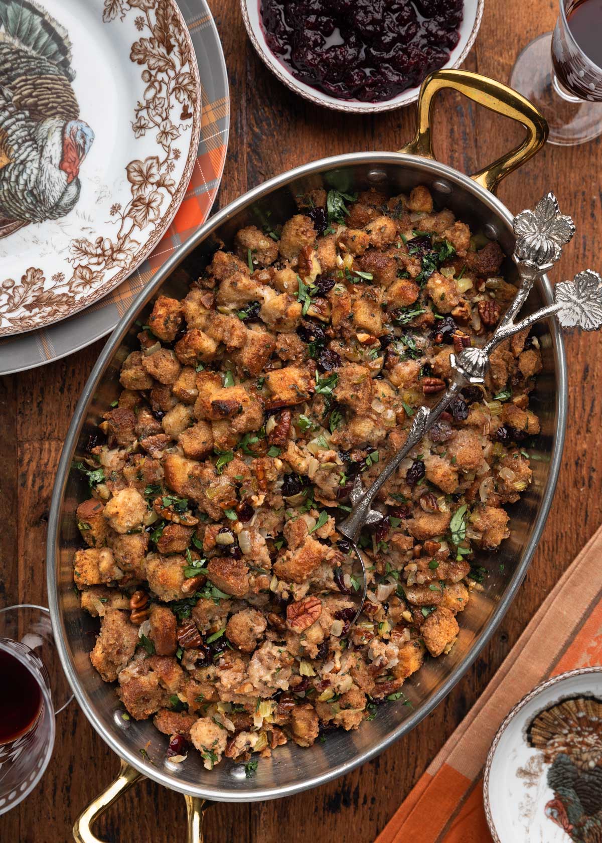 overhead photo of cranberry pecan stuffing in a copper gratin with an ornamental serving spoon