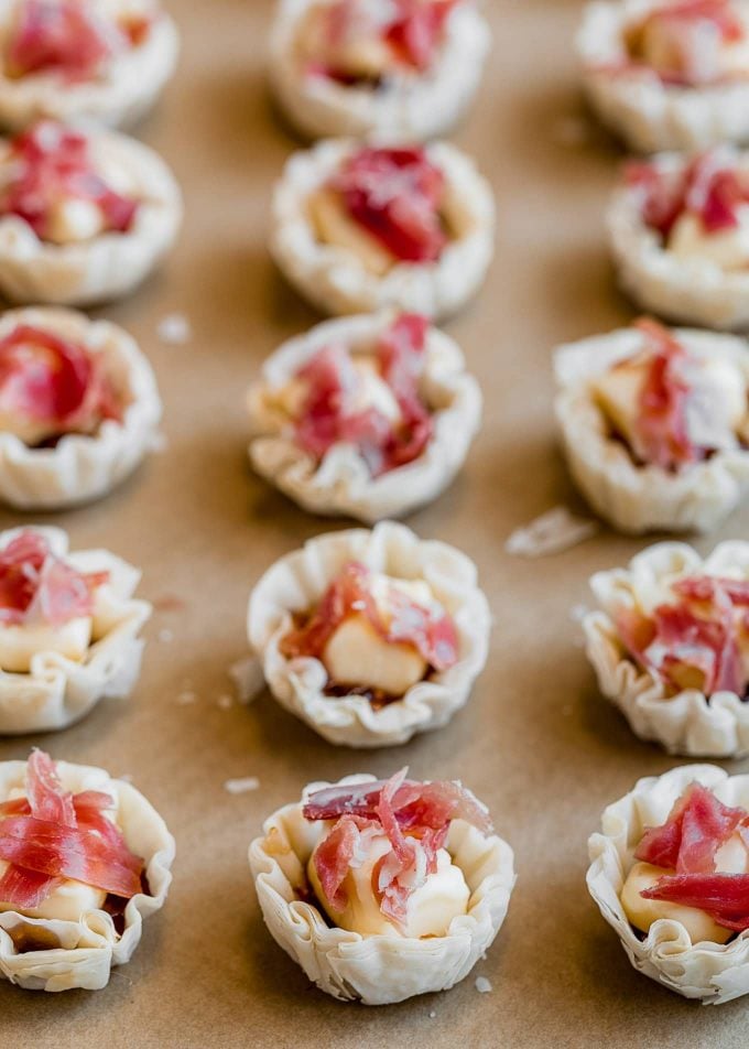 phyllo cups filled with brie and prosciutto on a baking sheet