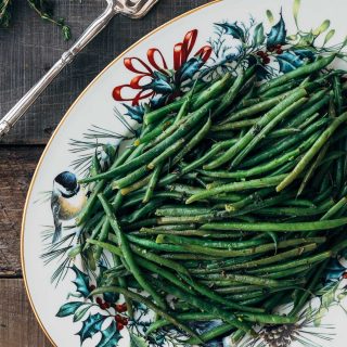 haricots verts on a Christmas serving platter with silver serving tongs