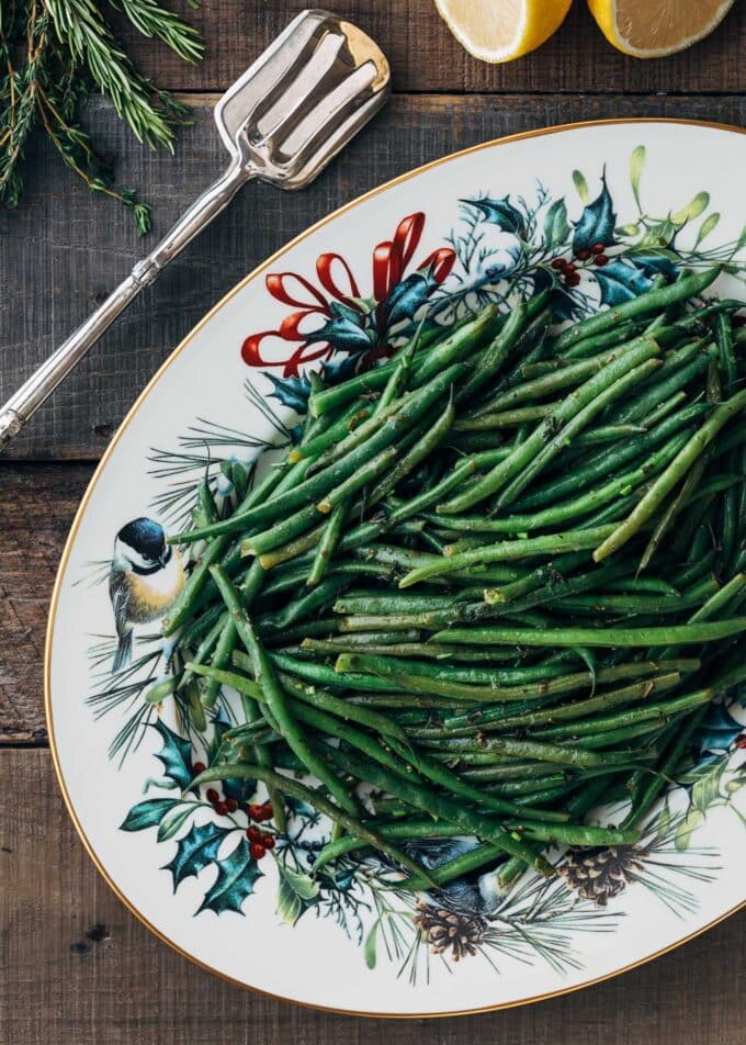 haricots verts on a Christmas serving platter with silver serving tongs