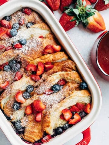 overhead of a croissant french toast bake with berries in a staub rectangular baker