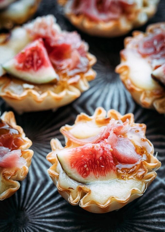 miniature phyllo brie bites with figs and prosciutto on a serving tray