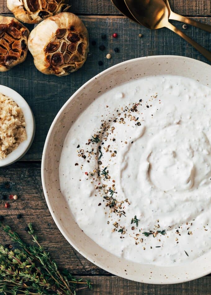 horseradish cream sauce in a bowl with roasted garlic heads and a bowl of horseradish on the side