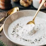 horseradish cream sauce with roasted garlic in an ivory bowl with a spoon