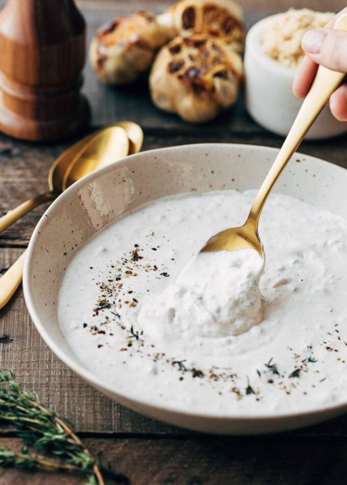 horseradish cream sauce with roasted garlic in an ivory bowl with a spoon