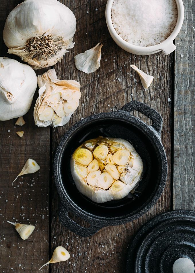 trimmed head of garlic in a cast iron cocotte with olive oil