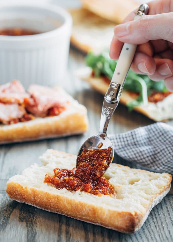 spooning pesto rosso onto ciabatta bread