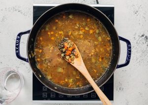 simmering a pot of lentil soup with broth and water