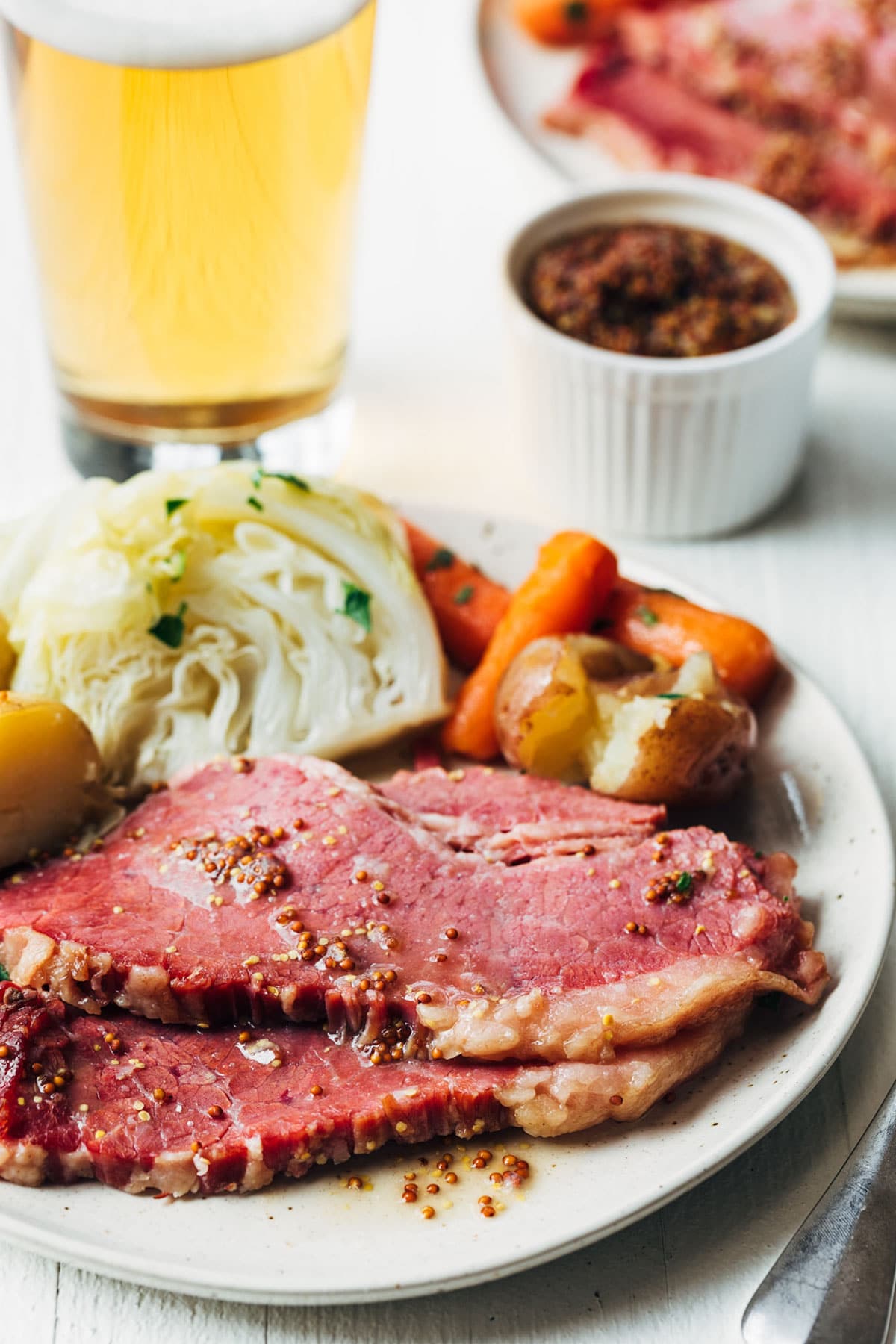 sliced corned beef on an ivory ceramic plate with potatoes, carrots, and cabbage