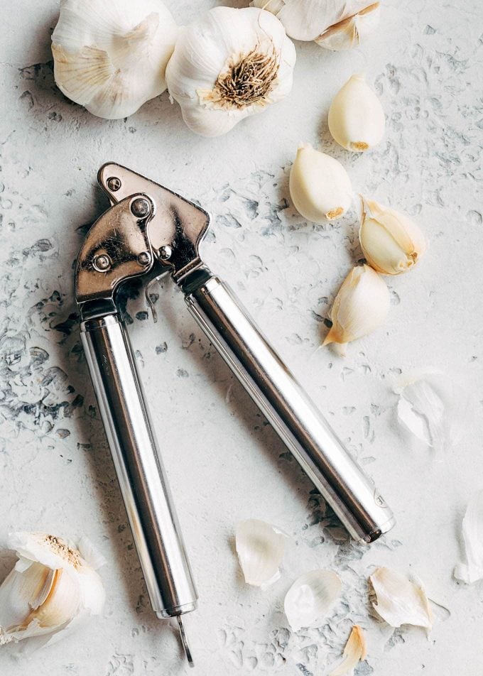 garlic cloves and a garlic press for scampi recipe