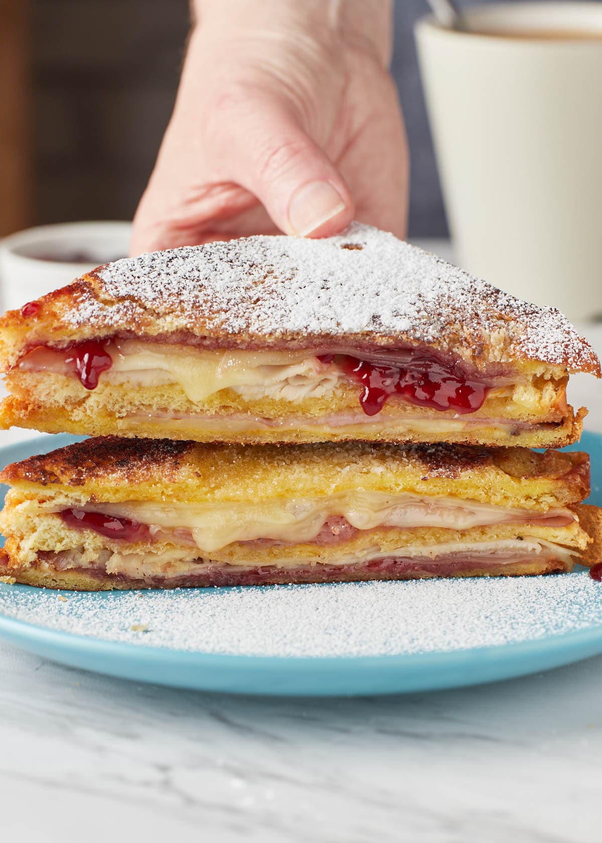 monte cristo sandwich on a teal plate with powdered sugar